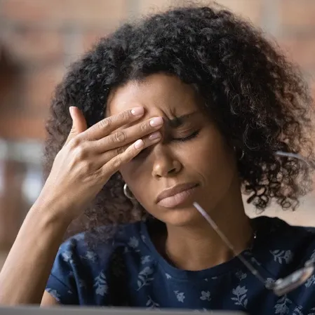 Woman With Headache Holding Glasses And Rubbing Forehead